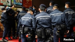 香港警察在逮捕《立场新闻》六名高管后站在该港媒办公楼外。(2021年12月19日)