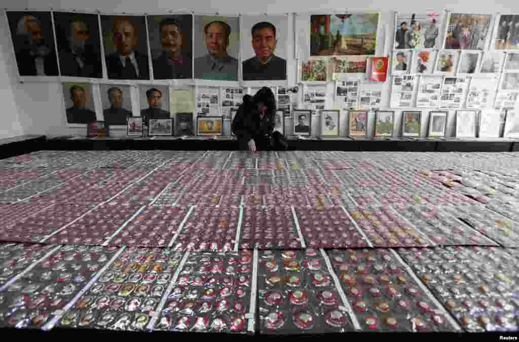 2011年11月29日,一位游客在中国云南省昆明市的一个红色博物馆观看毛泽东纪念章,墙上有马恩列斯毛和华国锋、刘少奇、周恩来和朱德的肖像。 