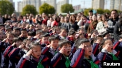 资料照:中国上海一所小学的学生们在新学期第一天举行的升旗仪式上敬礼。(2018年2月23日)