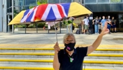 社运人士王婆婆9月15日在湾仔区域法院外撑起贴上英国国旗的黄伞,声援六四未经批准集结案,12名认罪的被告(美国之音/汤惠芸)