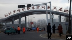 资料照片:居民们走过“和田市纺织服装实训就业基地”的入口。(2018年12月5日)