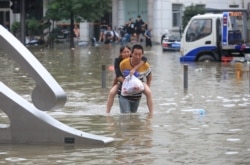 河南省郑州市一名男子背着一名女子趟过满是洪水的街道。 (2021年7月21日)