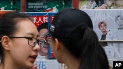 两位女子在展示中国领导人习近平和青春偶像鹿晗的杂志的一处北京报摊前聊天。(2017年10月22日)