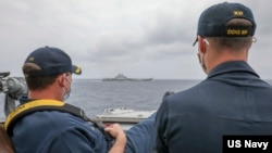 资料照片:美国海军公布的照片显示,两位美国海军中校罗伯特·J·布里格斯与理查德·D·斯莱2021年4月4日在阿利·伯克级导弹驱逐舰“马斯廷号”驾驶舱进行水面接触观察。照片中可见中国"辽宁号"航空母舰及其舷号。