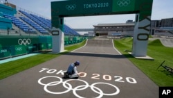 一名日本工人在东京奥运会举行赛跑的跑道上画奥运五环表示。(2021年7月20日)