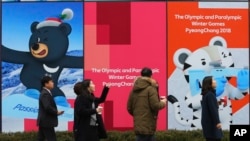 人们走过韩国首尔街道旁为平昌冬奥会竖起的广告牌。(2018年1月17日)