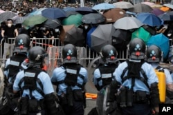 2019年6月12日在香港立法会附近,带有防暴装备的警察同打着雨伞的示威者对峙。