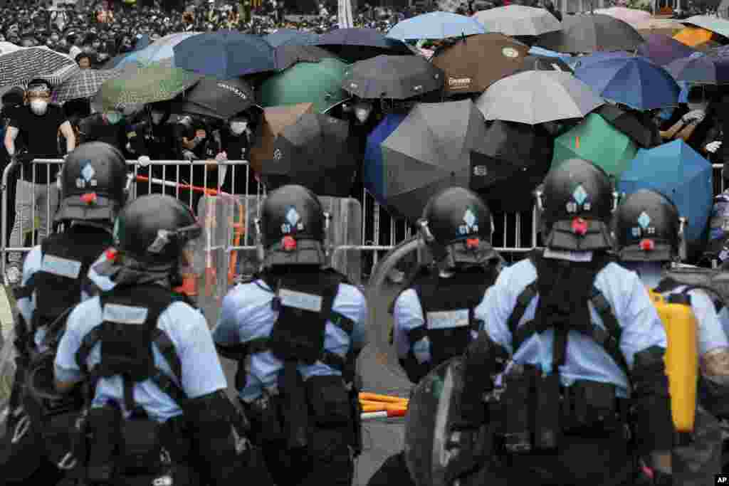 2019年6月12日在香港立法会附近,带有防暴装备的警察同打着雨伞的示威者对峙。