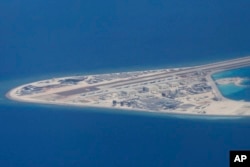 菲律宾空军一架运输机在南中国海南沙群岛的中国造的人造岛礁渚碧礁上空飞越时拍摄的照片,显示人造岛礁上的简易机场和建筑物。(2017年4月21日)