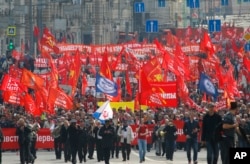 人们举着红旗和共产党的锤子与镰刀旗在莫斯科举行纪念五一节的集会。(2018年5月1日)
