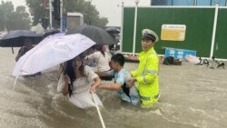河南省郑州市一名交通警察用一条绳子帮助居民过洪水湍急的街道。 (2021年7月20日)