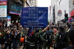 香港警察对在中国国庆日要求北京政府释放12港人的抗议者展示警示牌。(2020年10月1日)