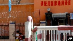 新疆喀什地区伽师县一所小学校门有铁丝网和监控镜头,校门前写着:请使用国家通用语言。(2018年8月31日)