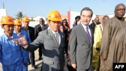 中国外交部长王毅(右二)在塞内加尔文化部长阿卜杜•阿西塞•姆巴耶(右一)的陪同下,参观中国投资的塞内加尔“黑人文明”博物馆的建筑工地。