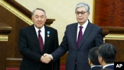 资料照:哈萨克斯坦现任总统托卡耶夫宣誓就职后(右)与卸任总统纳扎尔巴耶夫握手。(2019年3月20日)