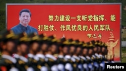 资料照:解放军士兵列队在中国领导人习近平画像以及他提出的“能打胜仗,作风优良”的口号前走过。(2015年8月22日)