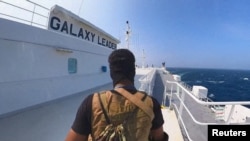 资料照:一名胡塞武装人员站在红海上行驶的“银河领袖号”货船上。(2023年11月20日)