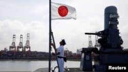 一名水手在日本加贺号直升机航母上升起日本国旗。(2018年9月30日)