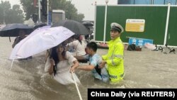 河南省郑州市一名交通警察用一条绳子帮助居民过洪水湍急的街道。 (2021年7月20日)
