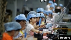 资料照:中国深圳一家工厂的工人在生产线上制造吸尘器。(2019年8月9日)