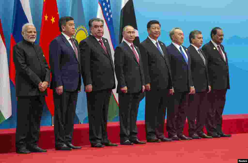 在中国山东省举行的上海合作组织成员国首脑会议合影。左起:印度共和国总理莫迪,吉尔吉斯斯坦共和国总统热恩别科夫,塔吉克斯坦共和国总统拉赫蒙,俄罗斯总统普京,中华人民共和国主席习近平,哈萨克斯坦共和国总统纳扎尔巴耶夫 ,乌兹别克斯坦共和国总统米尔济约耶夫,巴基斯坦共和国总统侯赛因(2018年6月10日)。 其中普京和纳扎尔巴耶夫都已经执政多年,本网的江泽民图集里有他们和江泽民的合影。如今他们继续掌权。