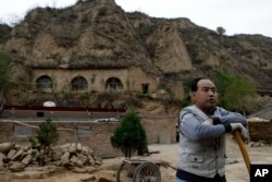 2012年10月18日,一个农民站在习近平青年时期在中国陕西省梁家河住过的窑洞附近。