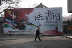 一名保安走过法治中国的广告牌。(2018年3月13日)
