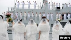 中国解放军海军人员在舟山一处军事基地举行的集体婚礼上挥手向他们的新娘告别。(2017年12月29日)