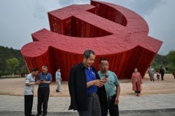 中国民众在延安附近的南泥湾树立的中共镰刀斧子党徽雕塑前拍照。(2021年5月11日)