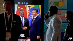 在北京举行中非合作论谈期间,非洲代表团成员走过正在播放中国国家主席习近平与埃塞俄比亚总理艾哈迈德握手的视频画面。(2018年9月3日)
