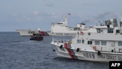这张拍摄于2023年8月22日的照片显示,中国海岸警卫队船只(左、右)在有争议的南中国海围堵了一艘由菲律宾海军包租的菲律宾民用船向菲律宾海军舰艇运送物资。