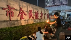 2024年11月12日,一位女士在珠海市全面健身广场外放置的鲜花旁点燃蜡烛,悼念死难者。一名男子驾驶越野车蓄意冲撞了在广场健身的人群。