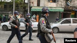 警察持枪走在甘马育镇法院外,法院正在就抗议期间被拘捕的一组记者举行听证。(2021年3月12日)