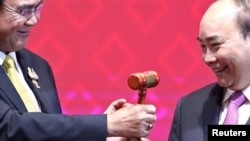 资料照片:在第35届东盟峰会及相关领导人会议的闭幕式上,越南总理阮春福从泰国首相巴育手中接过主席桘。