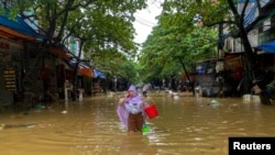 Một người dân lội trên đường phố ngập nước ở thành phố Thái Nguyên sau bão Yagi