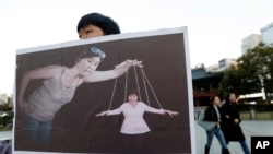 一名韩国大学生手举宣传画,展示韩国总统朴槿惠受其密友崔顺实控制