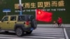 中国武汉街头一辆插着中国国旗的汽车从一名戴着口罩骑车的妇女身边驶过。(2020年1月29日)