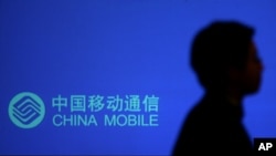 一名男子走过有中国移动标识的广告牌。(美联社照片)