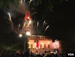 美国德克萨斯大学奥斯汀分校的毕业典礼上,礼花绽放,灯光辉映,地标性建筑顶部呈现橙色。(2017年5月20日)