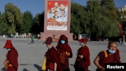 一群年轻的尼姑在拉萨的布达拉宫广场走过有着包括习近平在内的中国领导人的画像。(2021年10月15日)