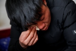 33岁的杨念连(音)在北京打工,居住在京郊马驹桥小区,除夕年夜饭期间与老家通电话。他说:“每次我回家,女儿最喜欢的事情就是和我聊天,她跑来跑去,听我讲在北京打工的所有事情。”(2021年2月11日)