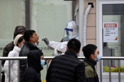 北京街头一处新冠病毒核酸检测点的医护人员在为一名男子进行检测。(2022年1月21日)