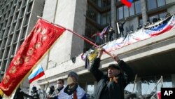 4月7日在乌克兰东部的顿涅茨克,活动人士在一座政府办公楼前挥舞前苏联和俄罗斯的国旗