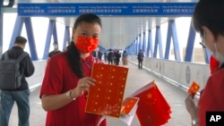 一名支持北京政府的女子在香港人行道上发放中国国旗。(2021年4月15日)