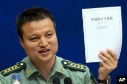 中国国防部发言人杨宇军手持《中国的军事战略》白皮书在新闻发布会上(2015年5月26日)