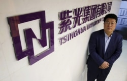 资料照:紫光集团董事长赵伟国站在该集团北京办公室的标识前。(2015年11月15日)