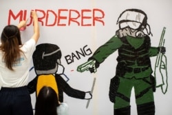 一名香港反送中抗议者在手绘一幅全副武装的蒙面港警开枪实弹射击一名抗议学生情景的壁画。(2019年10月2日)