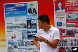 2018年8月22日,北京地铁站外的政府宣传广告牌宣传中国国家主席习近平和中国的经济成就,一名男子站在旁边。