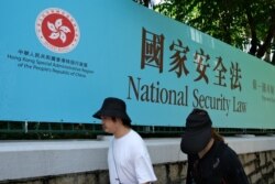 行人走过香港街头港版国安法的宣传牌。(2020年7月15日)