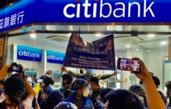 8-31事件一周年,一批警员冲入太子地铁站出口附近一间银行分行,高举旗帜警告在场人士涉嫌非法集会 (美国之音/汤惠芸)